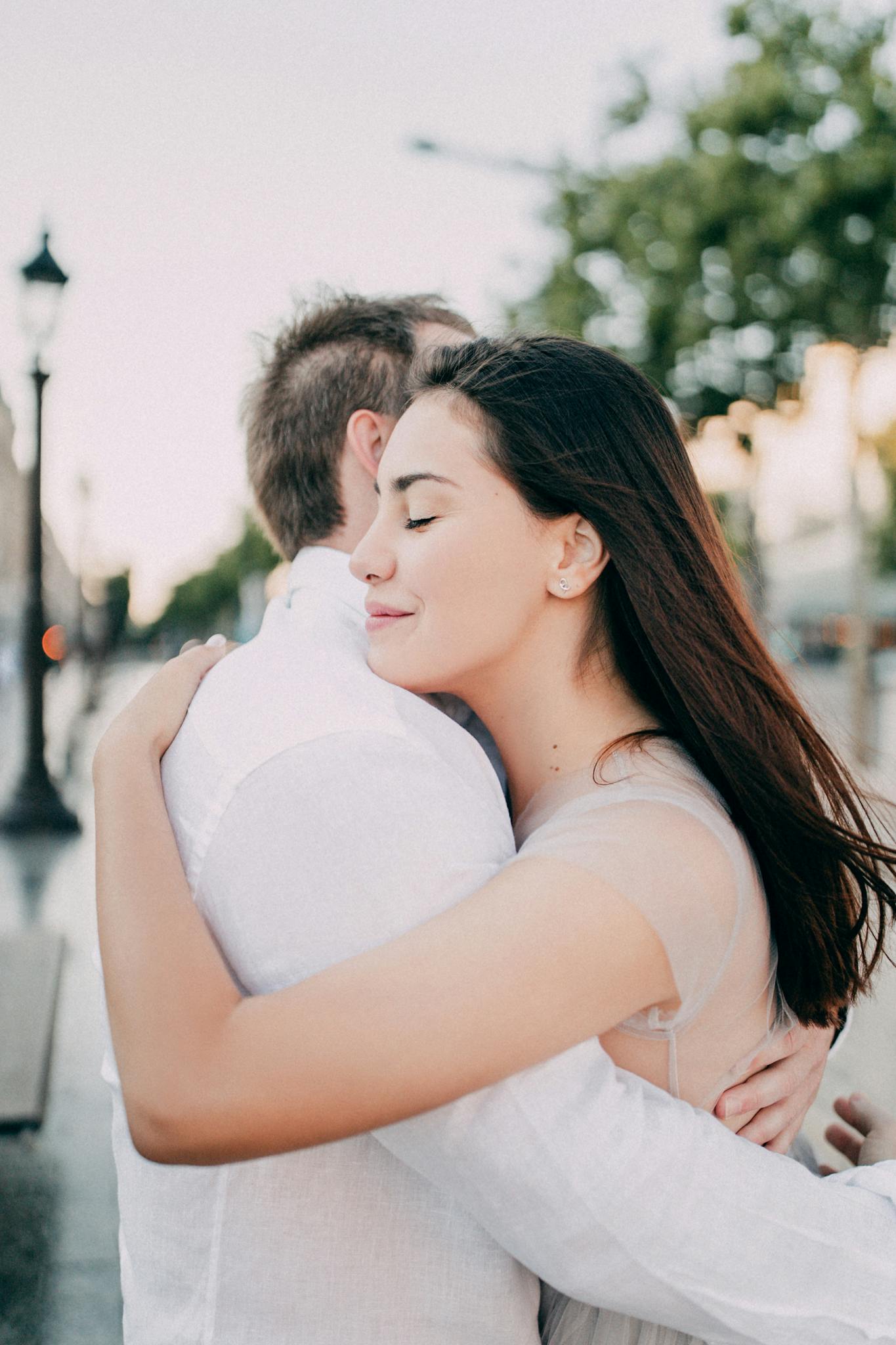A bride and groom embrace lovingly in an outdoor setting, showcasing romantic wedding photography.