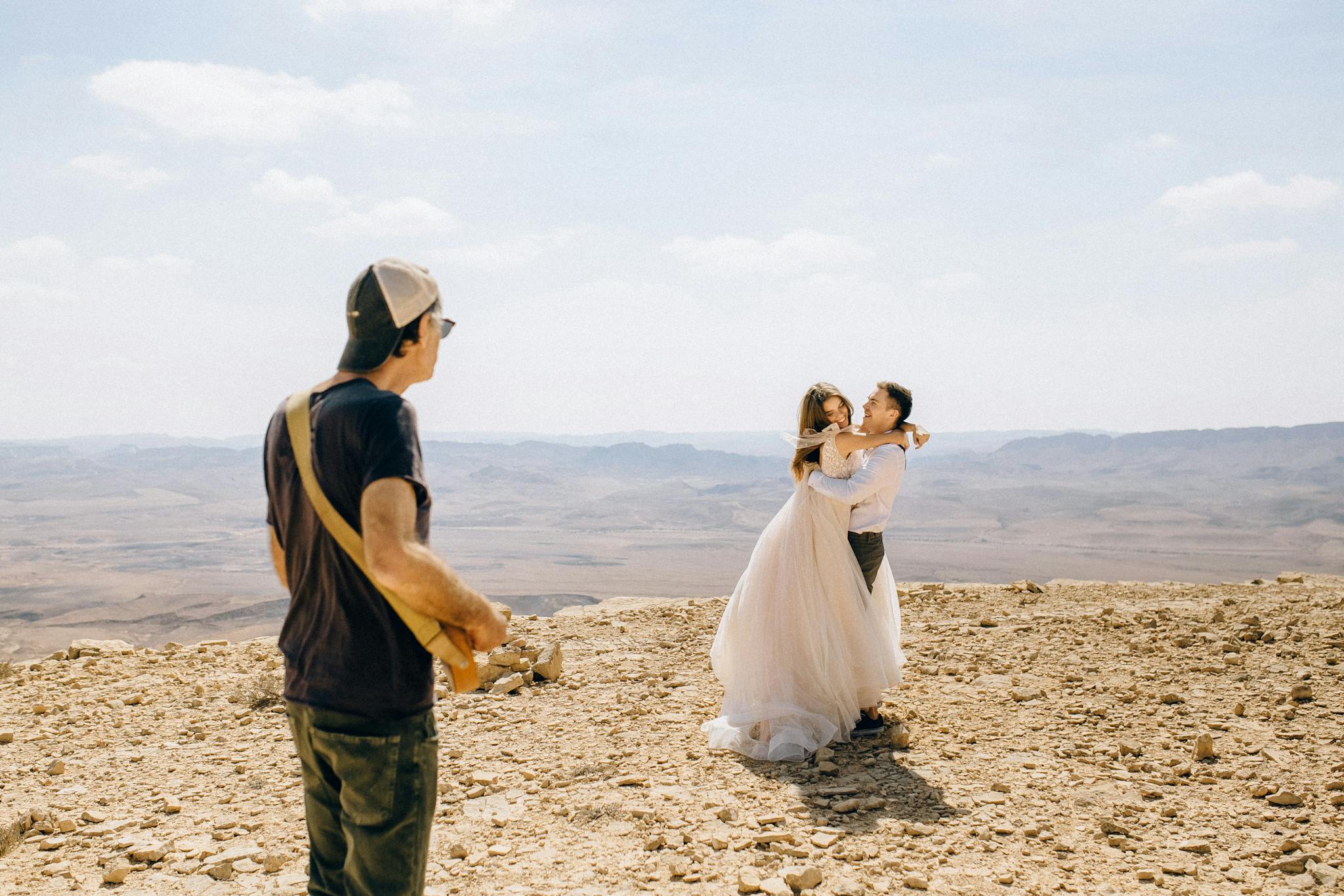 A couple's romantic wedding shoot in a stunning desert landscape with a photographer capturing the special moment.