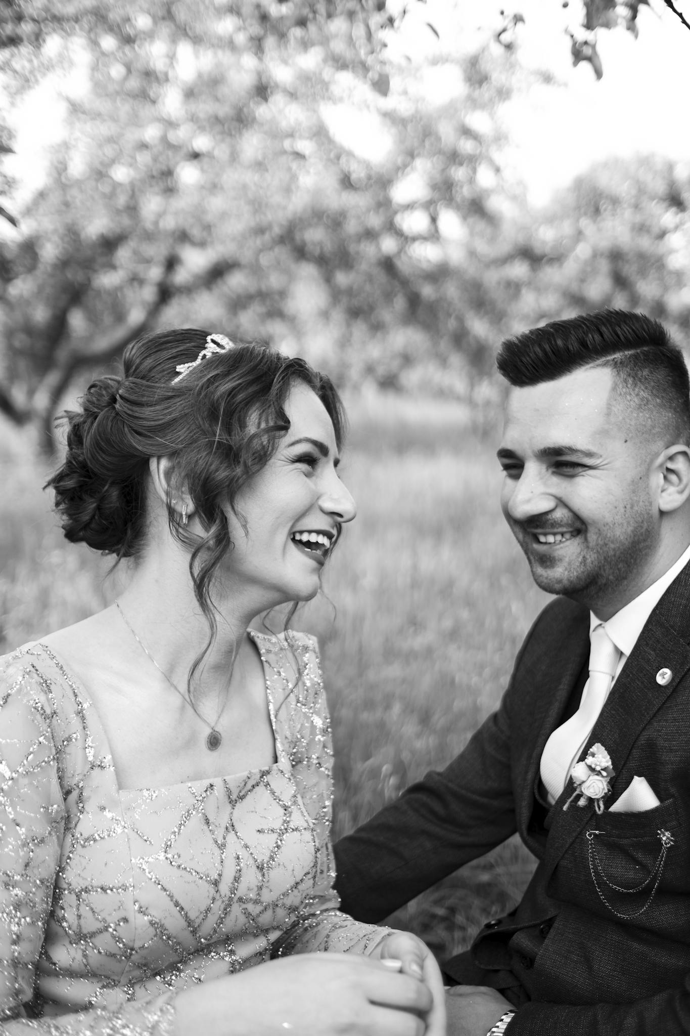 Happy couple laughing in a black and white outdoor wedding portrait, capturing a joyful moment.